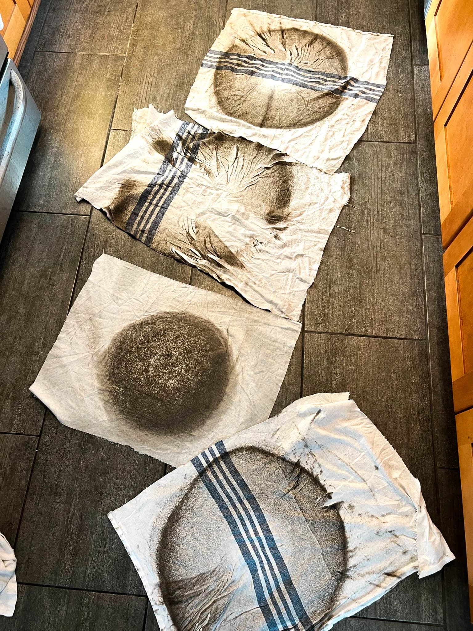 Four cleaning pads covered in dark grime pulled from a hardwood floor during a Cal Coast Flooring deep clean
