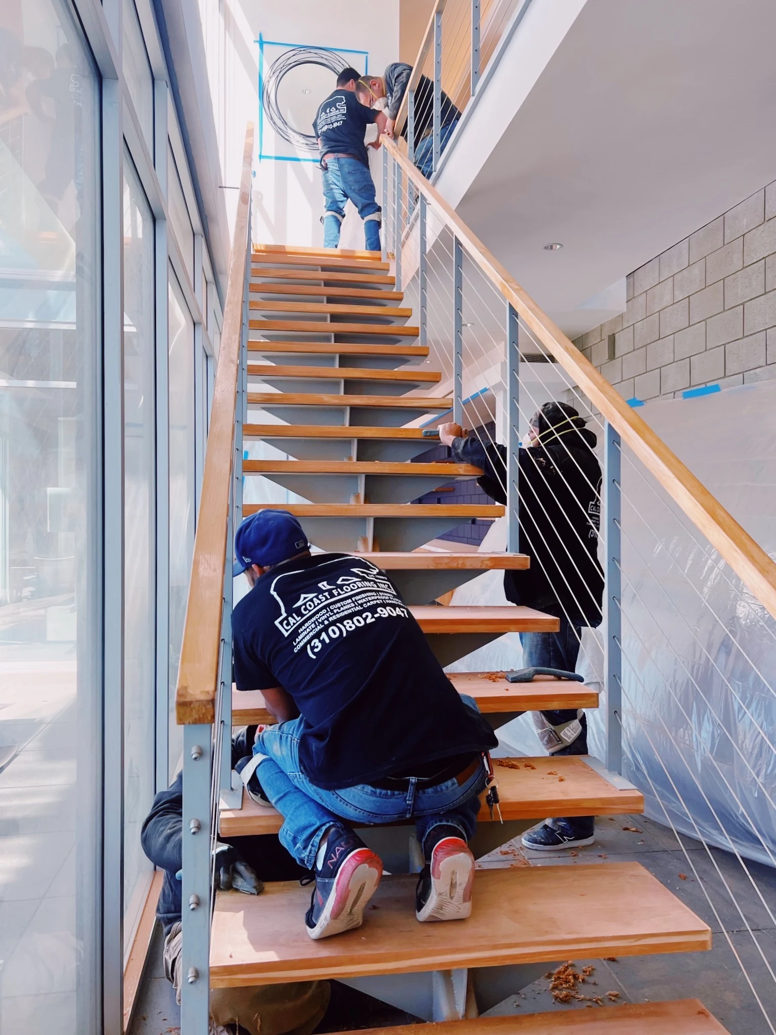 Cal Coast Flooring crew installing treads on a floating cable-rail staircase